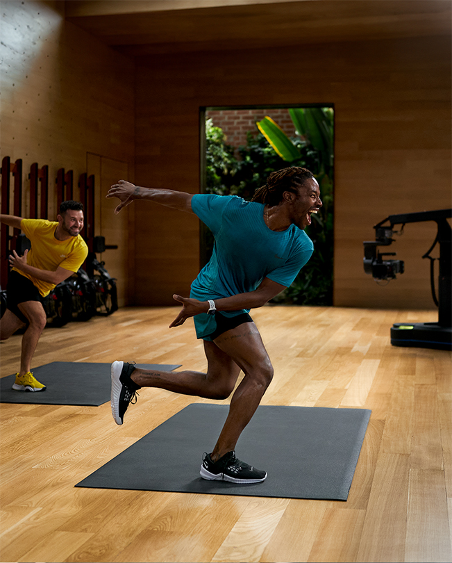 Tränare på Apple Fitness+ som leder ett pass framför kamerorna i en videostudio. 