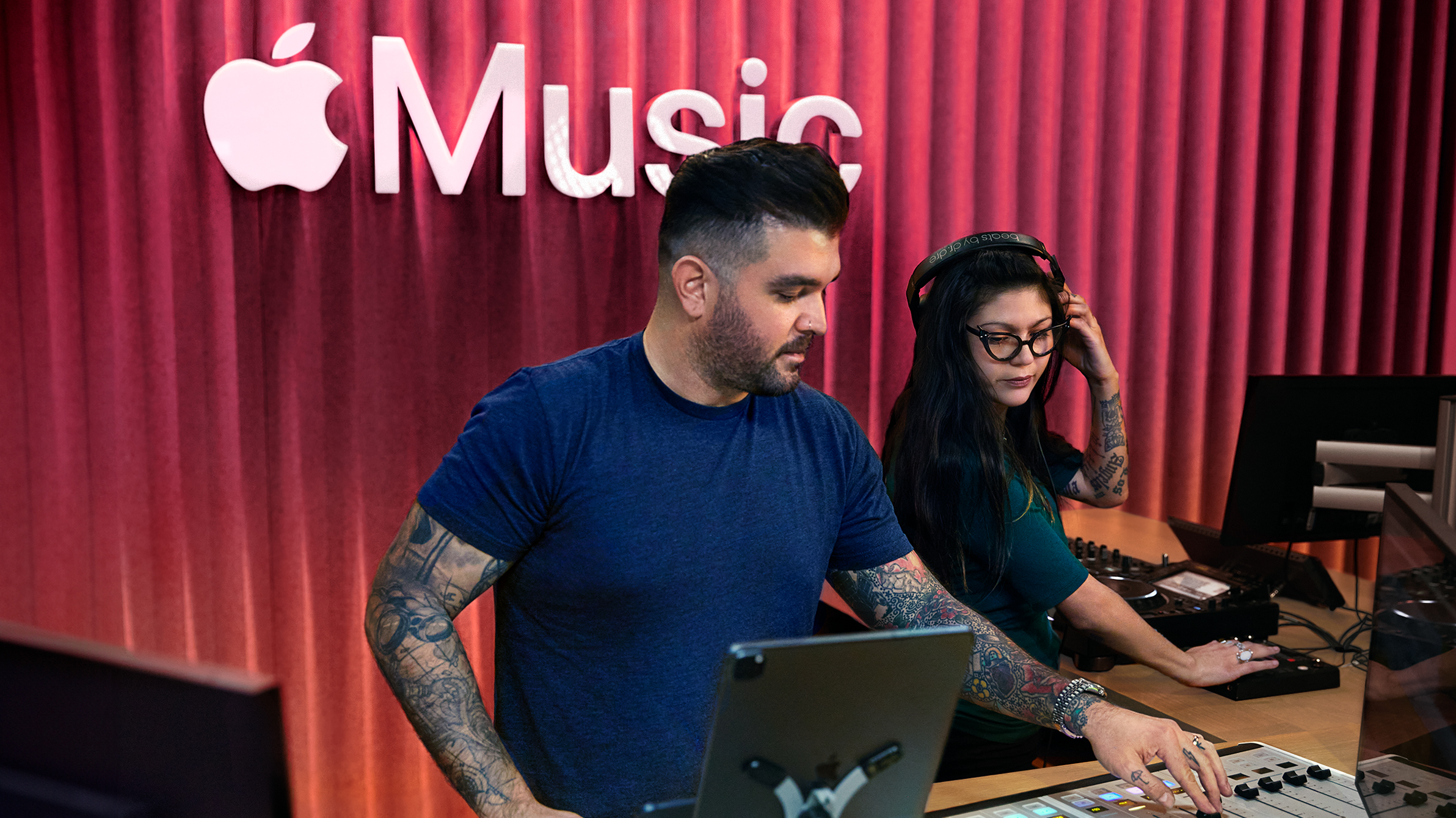 Dois colegas da Apple a usar uma mesa de mistura de som num estúdio Apple Music.