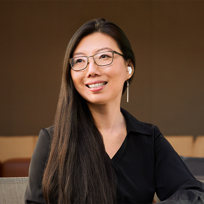 Jessica sitting outdoors with an office area in the background, smiling and looking off to her right.