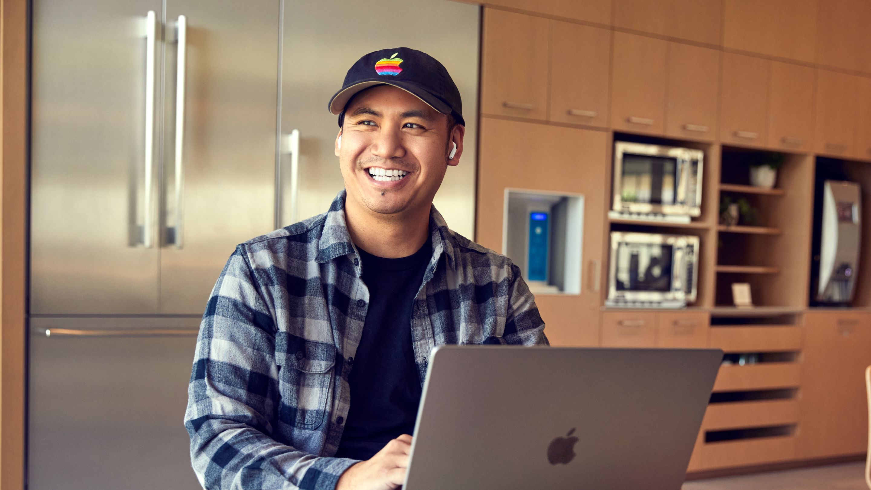 Zaměstnanec Apple San Diego se usmívá při práci na notebooku.