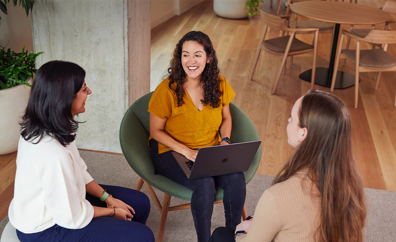 Tres empleadas de Apple hablan sentadas en una mesa.