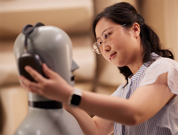 An Apple Hardware employee fitting Apple AirPods Max headphones on a mannequin in a lab.