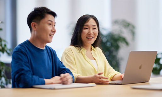 同僚と話をしているクリス。2人ともMacBookの前に座っている。