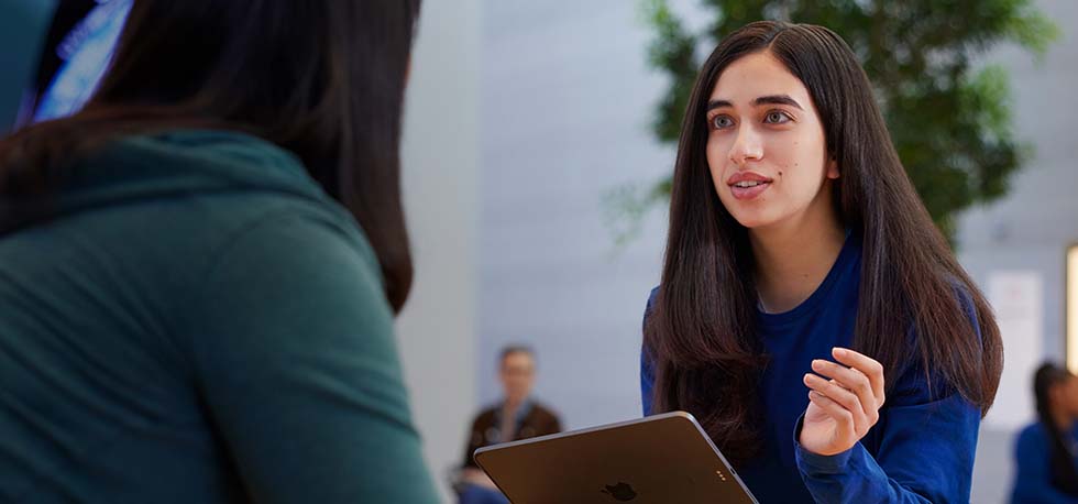 Serene sostiene un iPad y habla con una cliente.