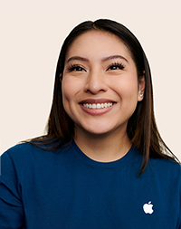 Persona del equipo de Apple Retail con el pelo a la altura del hombro y sonriendo a la cámara.