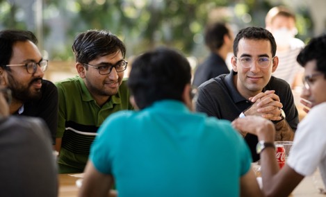  Un grupo de estudiantes en prácticas de Apple mantiene una animada conversación alrededor de una mesa en un Caffè Macs.