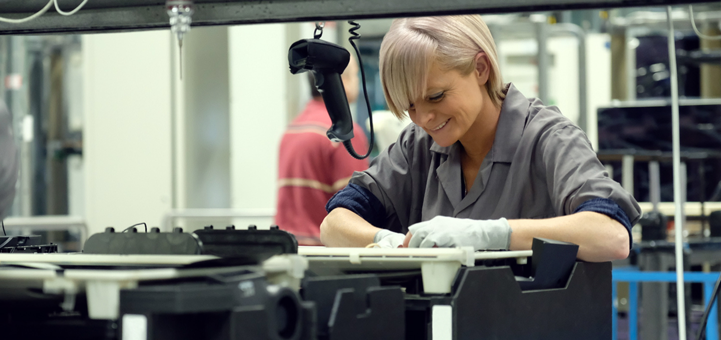 In an Apple manufacturing facility, two employees examine aluminum MacBook shells on titanium anodizing racks