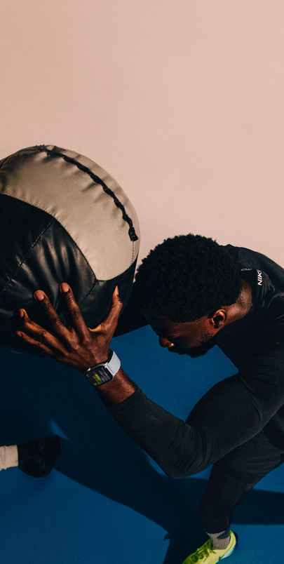 Un homme portant une Apple Watch Series 10 tient une medicine-ball pendant un entraînement.