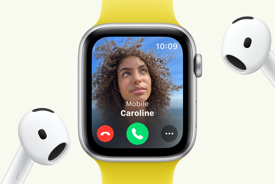 Apple Watch SE s prikazom dolaznog poziva pokraj para slušalica AirPods