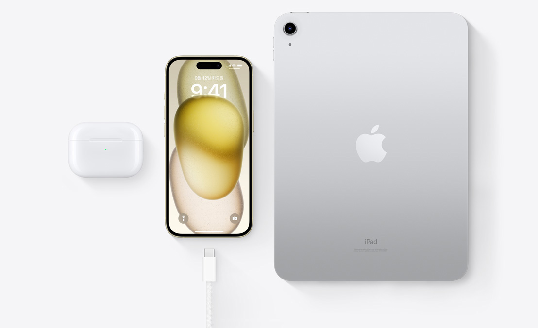 USB-C 커넥터를 갖춘 AirPods Pro, iPhone 15, iPad를 위에서 아래로 내려다본 시점을 통해 세 기기 모두 동일한 USB-C 케이블로 충전할 수 있음을 보여주는 모습.