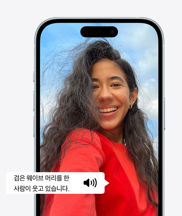 웨이브 머리를 하고 웃고 있는 사람의 모습을 VoiceOver를 사용해 자세하게 묘사하고 있는 iPhone 사진.