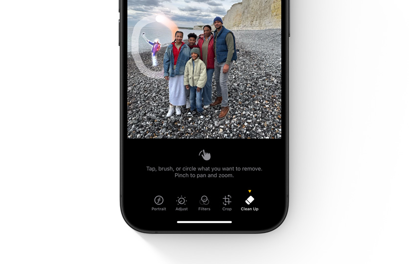 Un doigt touche un objet situé à l’arrière-plan dans une photo affichée sur iPhone pour indiquer ce qui doit être effacé