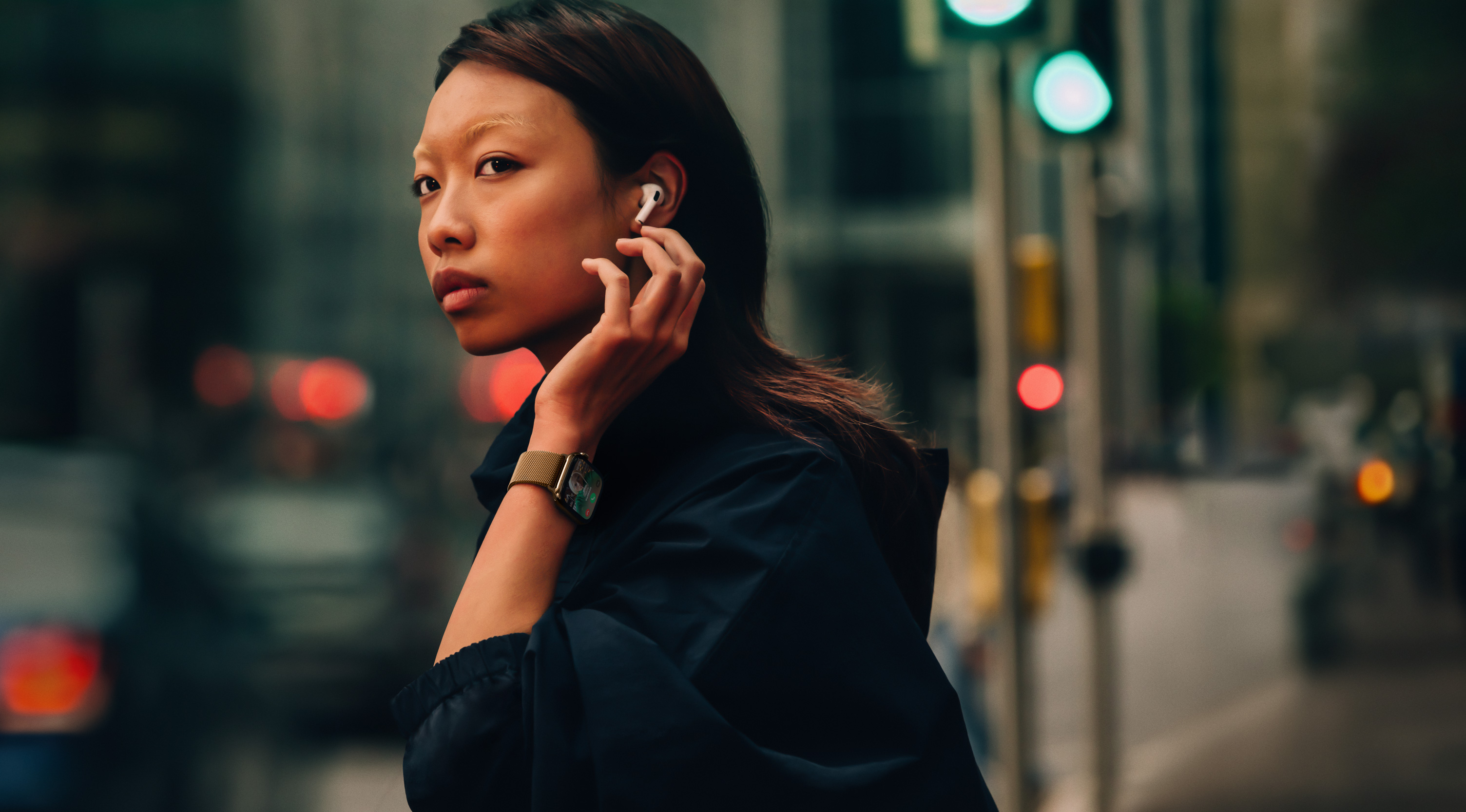 Eine Frau auf der Strasse, die eine Apple Watch Series 10 und AirPods trägt.