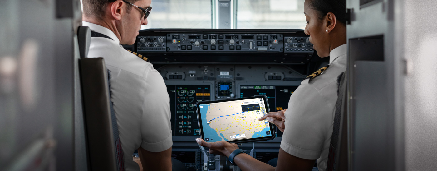 Twee piloten in een cockpit kijken naar een iPad met een kaart erop.