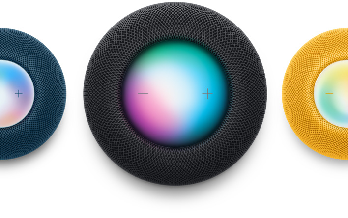 Un HomePod mini bleu, un HomePod couleur minuit et un HomePod mini jaune photographiés en vue plongeante. Siri est activé.