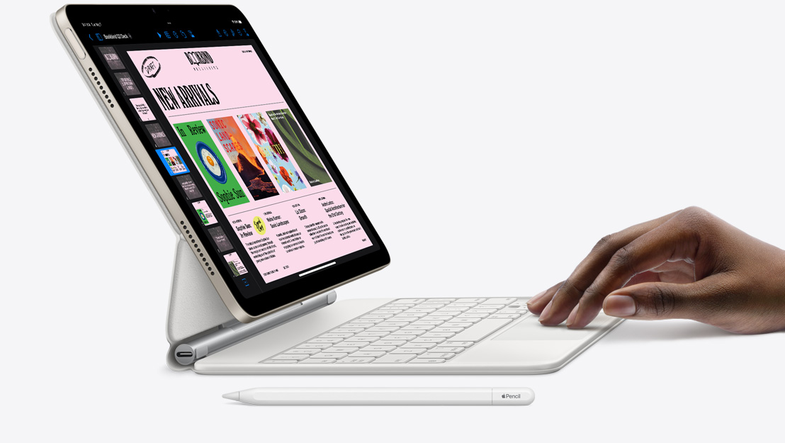 Страничен поглед към iPad Air с Keynote приложението, свързана Magic Keyboard клавиатура и опряна на тракпада ръка, като Apple Pencil е оставен наблизо.