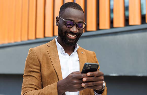 Confident African American businessman using smart phone in urban setting