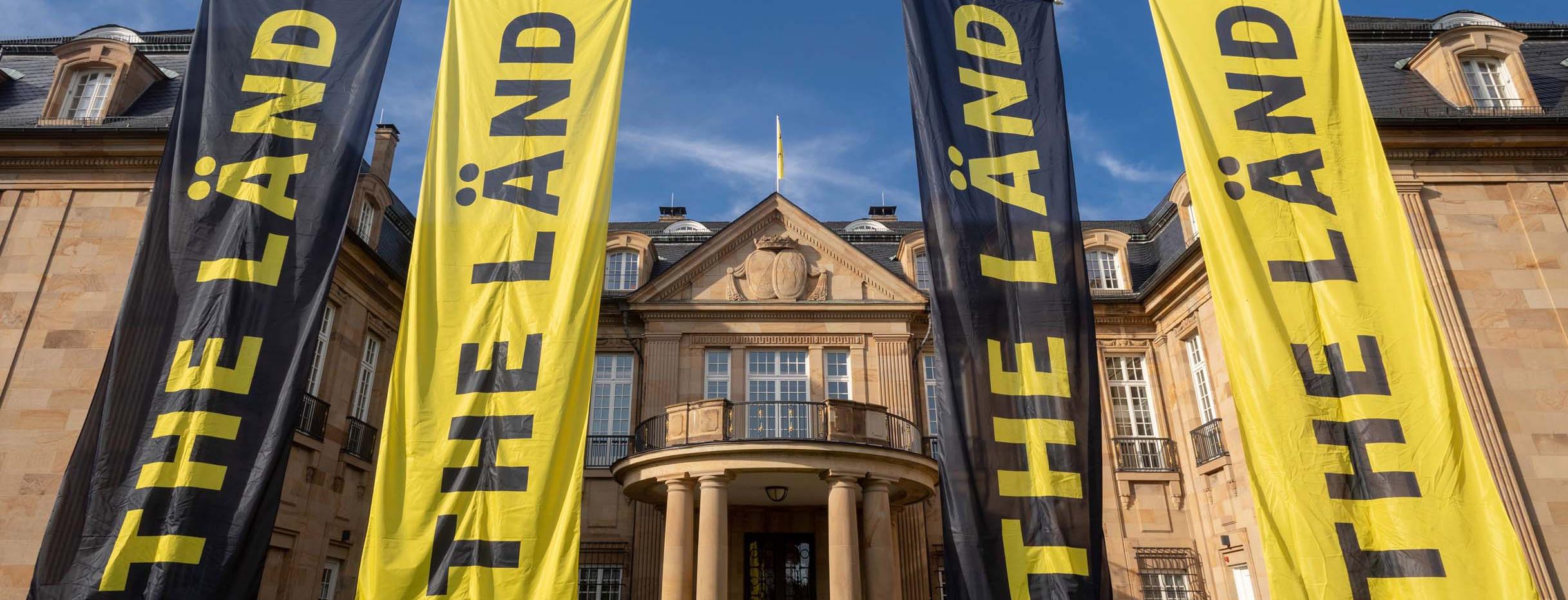 Vier Fahnen mit der Aufschrift „THE LÄND“ vor der Villa Reitzenstein in Stuttgart.