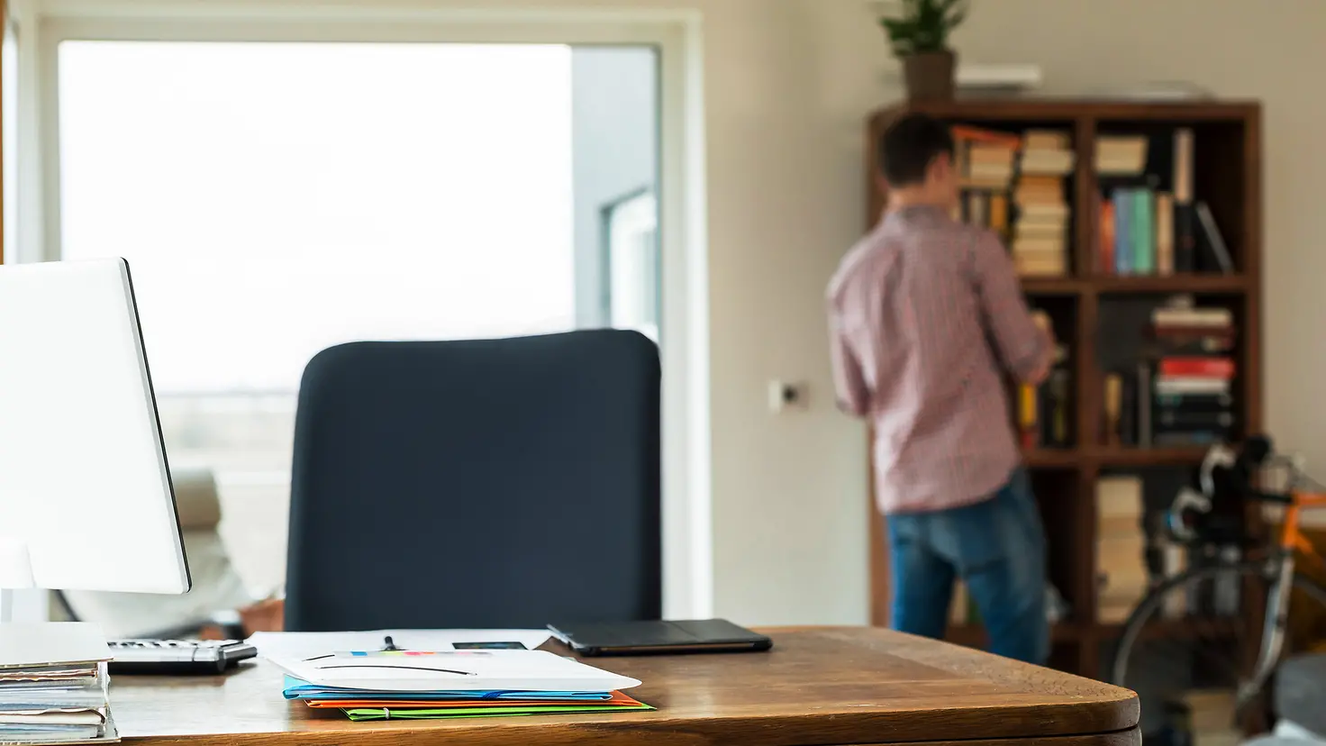 Student in seiner Wohnung mit Bücherregal und PC