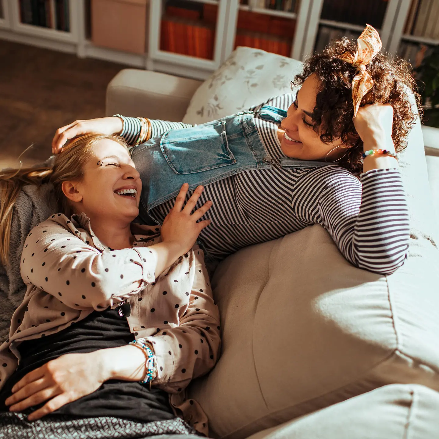 Zwei Frauen kuscheln und lachen auf einer Couch