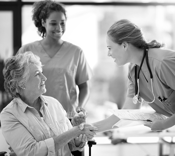 A doctor smiles while greeting her patient with a handshake