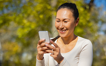 A woman smiles while watching video about improving her well-being on her phone.