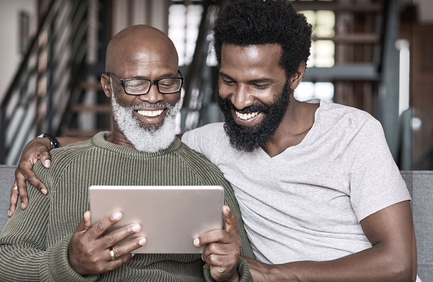 Father and son look at computer tablet as they look for Blue Cross Blue Shield of Michigan plans for Medicare, individuals and families.