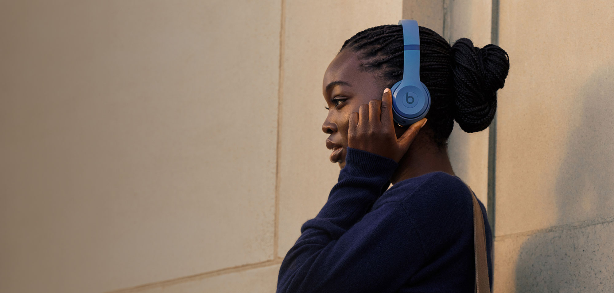 Person wearing Solo 4 headphones standing against a wall