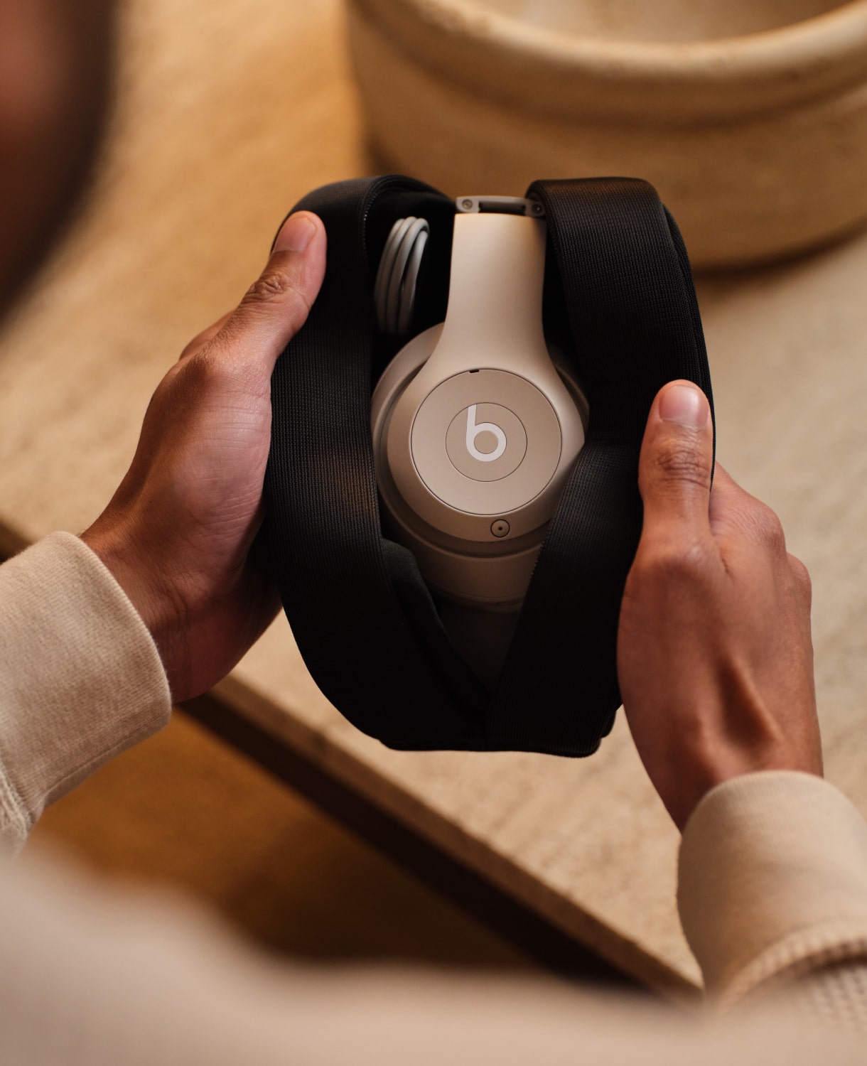 Persoon die de Beats Studio Pro Wireless-koptelefoon in de kleur zandsteen vasthoudt