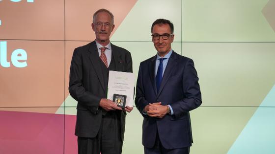 Bundesminister Özdemir steht mit  Dr. Felix Prinz zu Löwenstein auf der Bühne, Dr. Felix Prinz zu Löwenstein hält die Urkunde und die Professor Niklas-Medaille in die Kamera