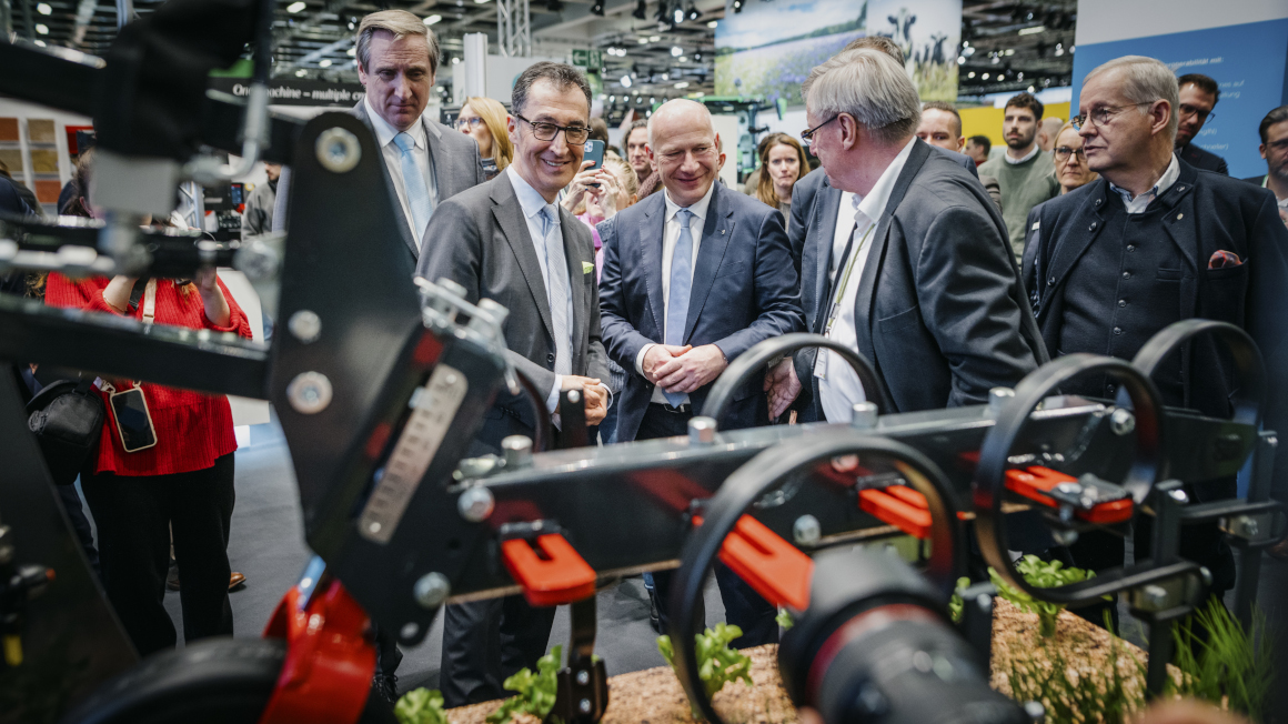 Bundesminister Özdemir beim Eröffnungsrundgang der Grünen Woche an einem Stand mit einem landwirtschaftlichen Roboter