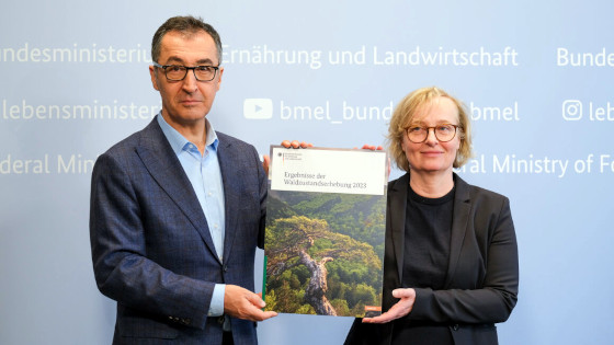 Bundesminister Cem Özdemir hält mit Frau Dr. Nicole Wellbrock vom Thünen-Institut die Waldzustandserhebung in die Kamera