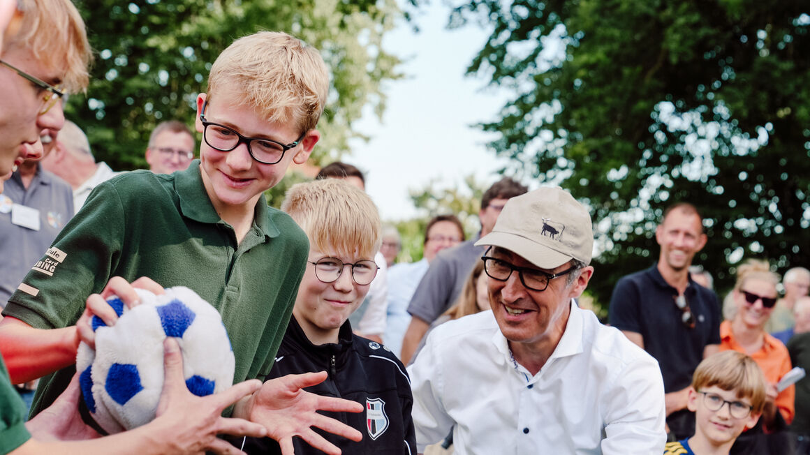 Bundesminister Özdemir mit Kindern, die einen Ball halten.