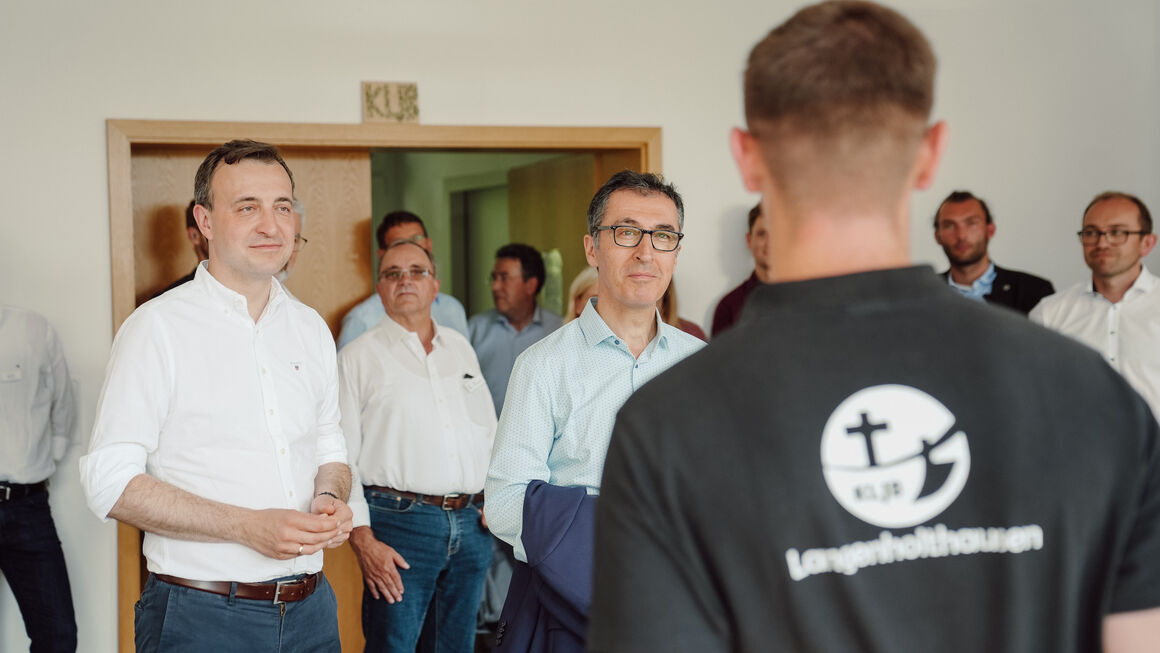 Bundesminister Cem Özdemir und der Bundestagsabgeordnete Paul Ziemiak im Gespräch mit einem Jugendlichen, im Hintergrund weitere Personen.