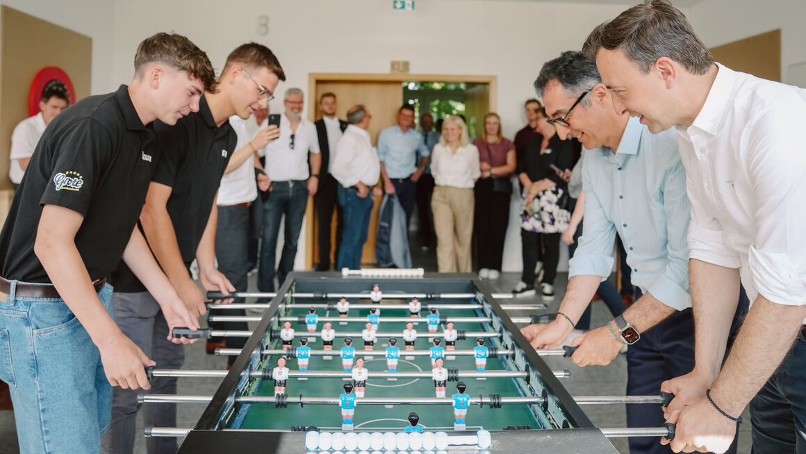 Bundesminister Cem Özdemir und Paul Ziemiak spielen Tischkicker mit zwei Jugendlichen. Andere schauen zu.