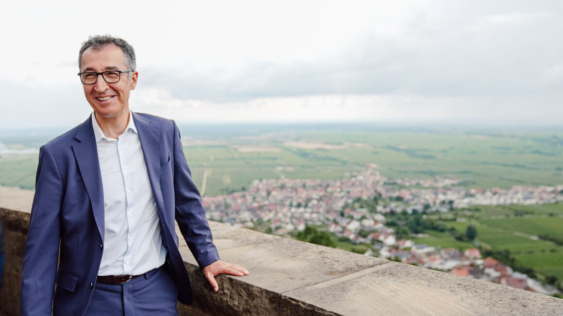 Bundesminister Cem Özdemir steht an der Brüstung des Hambacher Schlosses, mit Blick über Hambach