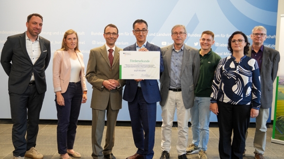 Gruppenbild, Bundesminister Özdemir hält den Förderbescheid Forschung zu klimafreundlichem Backweizen  in den Händen