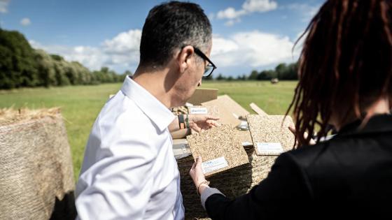 Bundesminister Cem Özdemir und eine Frau betrachten Pressplatten aus Paludikultur.