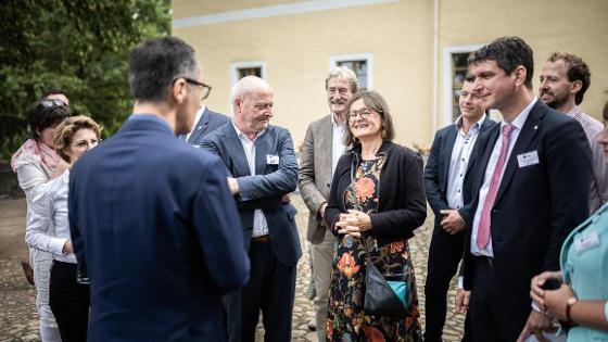 Austausch beim Besuch in Thallwitz: Bundesminister Cem Özdemir ist in der Rückansicht zu sehen wie er sich mit einer Personengruppe unterhält.