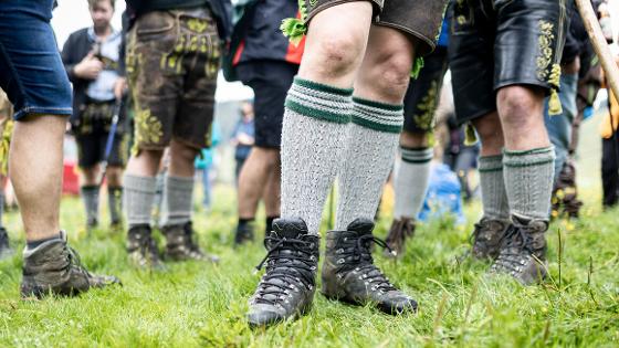 Blick auf Männerbeine in Trachtenlederhosen mit Kniestrümpfen und Wanderschuhen