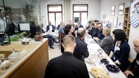 Gruppenbild: Bundesminister Cem Özdemir sitzt mit weiteren Personen an einer Kaffeetafel in einer ehemaligen Bank.