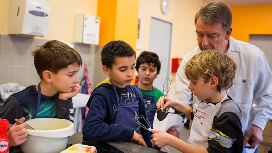 Jungs lernen in einer Schulküche das Kochen