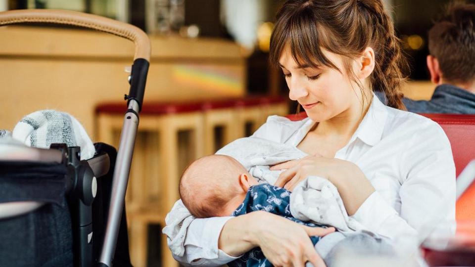 Stillende Frau mit Baby und Kinderwagen in Restaurant