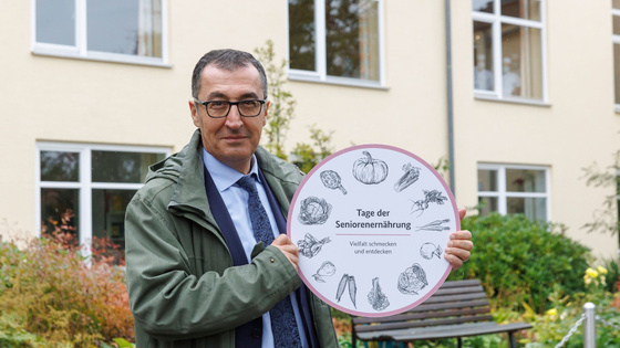 Bundesminister Cem Özdemir häl ein Schild zum Tag der Seniorenernährung hoch