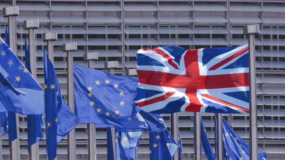 eine Flagge Großbritanniens und mehrere EU-Flaggen flattern im Wind