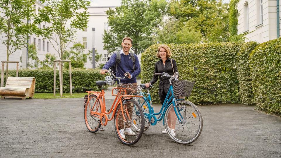 Ein Mitarbeiter und eine Mitarbeiterin des BMEL stehen mit ihren Fahrrädern im Innenhof des Ministeriums