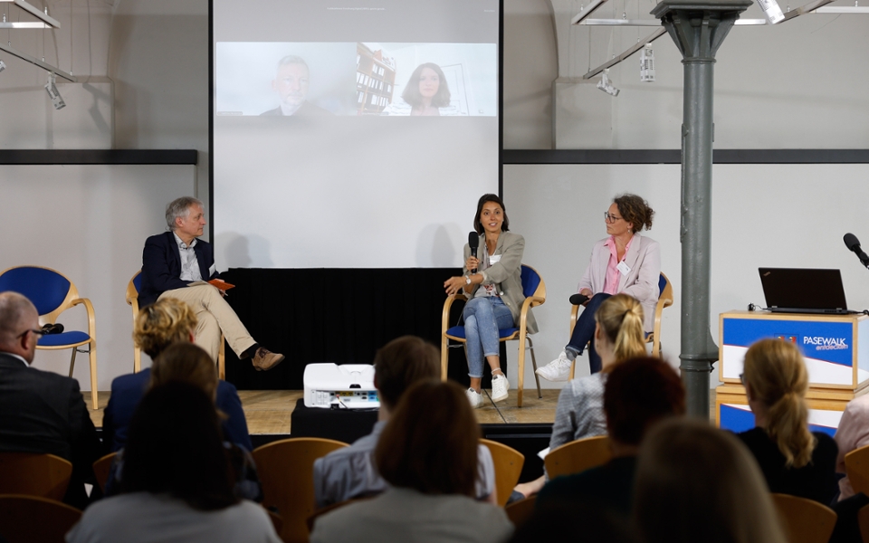 Angeregte Gesprächsrunde auf der Fachkonferenz "Forschung Digital". Drei Leute sitzen auf der Bühne in Pasewalk und zwei weitere Personen sind digital zugeschaltet.