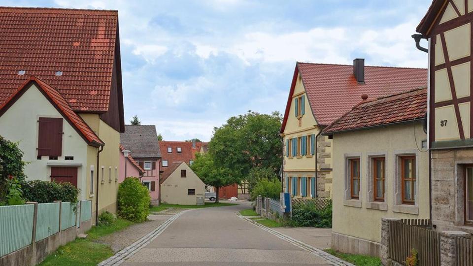 Blick entlang einer Straße im Dorf, die an beiden Seiten von Gebäuden gesäumt ist.