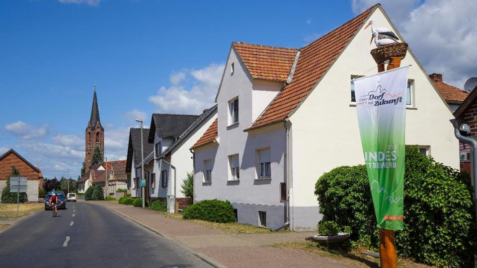 Blick über die Dorfstraße auf den Kirchturm der Gemeinde