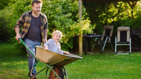 Vater schiebt Sohn in einer Schubkarre